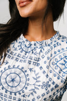 Close-up of blue embroidered eyelet detailing and scalloped edge on the short layered sleeve of the white midi dress.