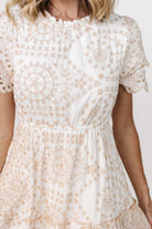 Three-quarter view showing embroidered eyelet detail, layered scallop sleeves, keyhole back closure, and hidden side pockets on the white midi dress.