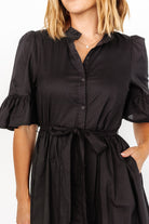 Three-quarter view of the Mirielle midi in black highlighting the single-tier skirt, ruffled cuffs, and functional side pockets.