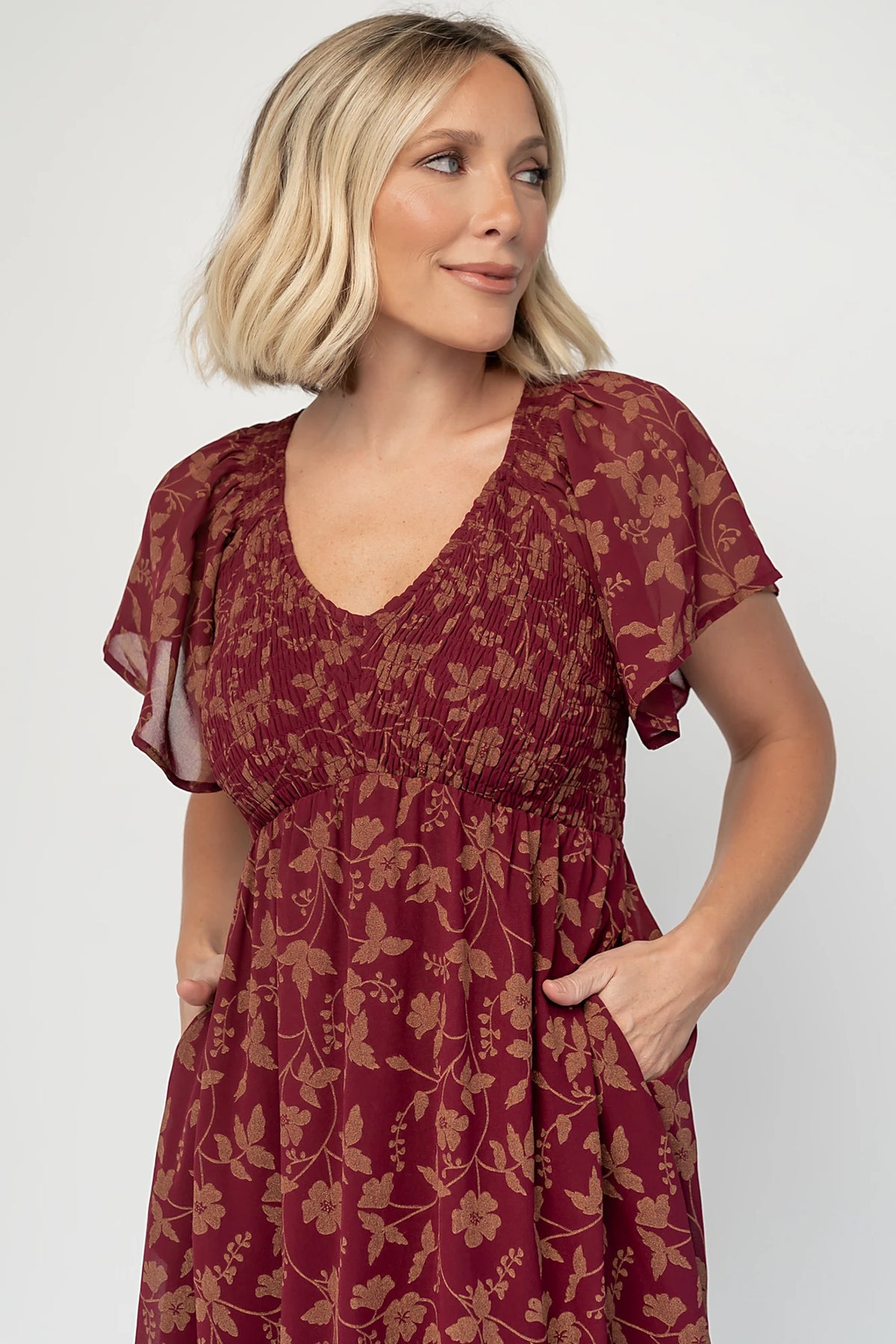 Monica Smocked Dress in Wine + Gold with V-neckline, smocked bodice, flutter sleeves, high waist, and tiered skirt.