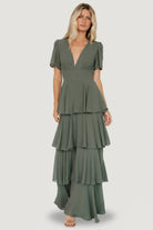 Model posed in Dark Sage Montaigne Ruffle Maxi Dress showing side profile of cascading ruffles, contoured underbust and smocked back with gentle, flowing chiffon drape.