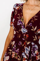 Three-quarter view of mulberry floral maxi showing asymmetrical cascading ruffles, short flowy sleeves, and the dress’s soft drape and print detail.