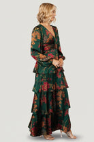 Close-up of emerald floral print on satin fabric showing copper and rose floral details and smooth, lustrous texture.