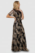 Side profile of maxi-length skirt with full sequin coverage, lined body, and sheer short sleeves for light, elegant movement.