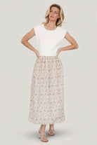 Front view of Myra sweater dress in ivory with coral, blue and green floral print, short cap sleeves and elastic waist, pockets visible.