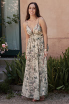 Side-angle full-length shot of Naia Maxi Dress showing high waistline, smocked back, and flowy maxi skirt in natural and sage tones.