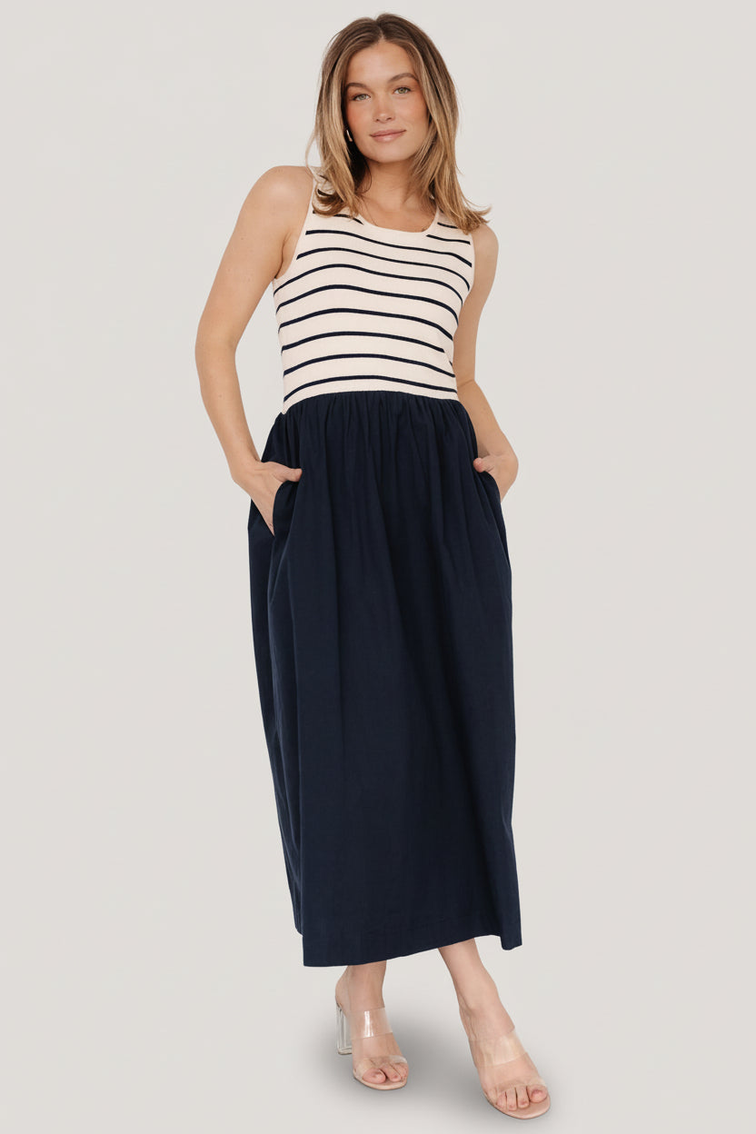 Front view of navy stripe tank dress on model showing sweater-knit bodice, scoop neckline, elastic waist and midi skirt with hidden pockets.