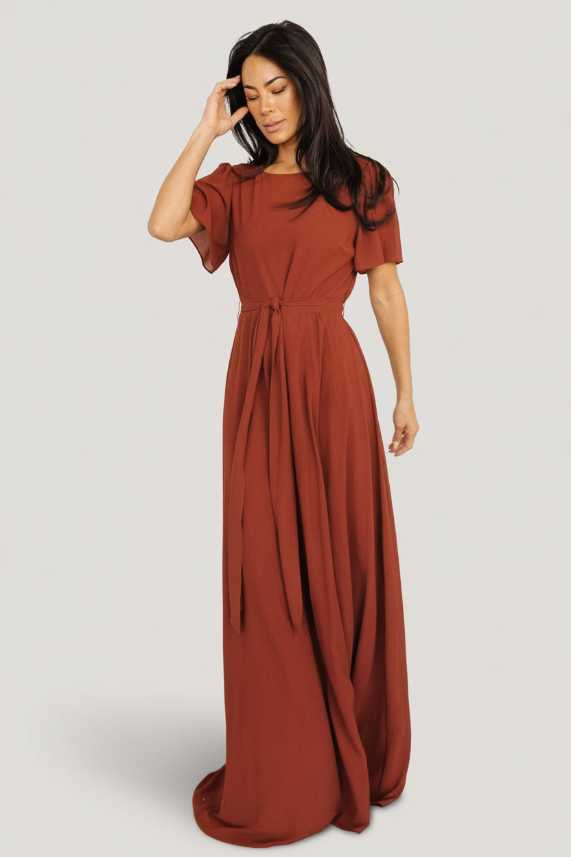 Full-length studio image of Naomi cinnamon chiffon maxi dress showing silhouette, rounded neckline, and full lining.