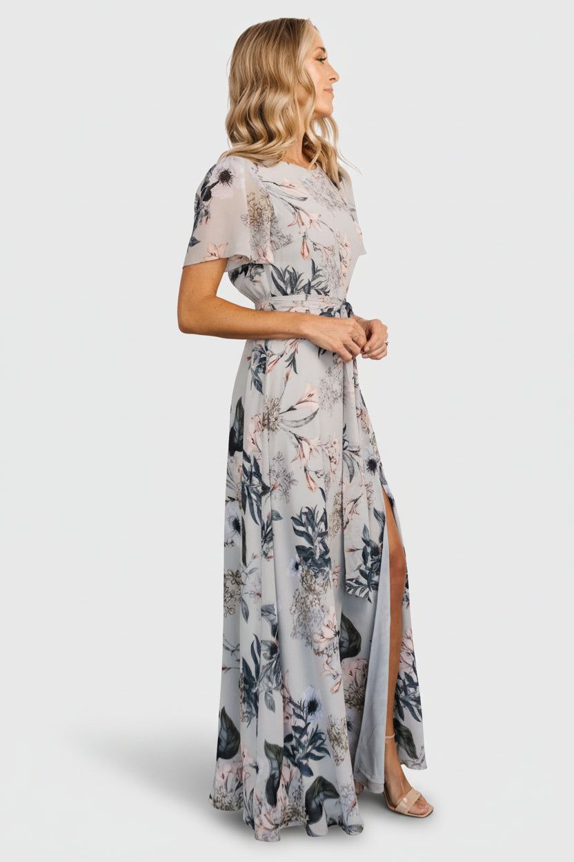 Full-length angled shot of the Naomi pale blue floral maxi dress on model, showing overall fit, sleeve length, and flowy skirt with soft print.