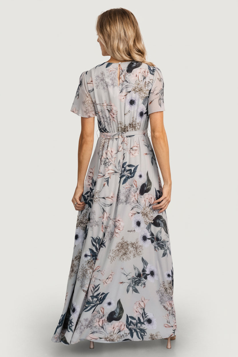 Side view showing left leg slit and skirt sweep of the Naomi pale blue floral maxi dress, illustrating movement and ankle-length coverage.