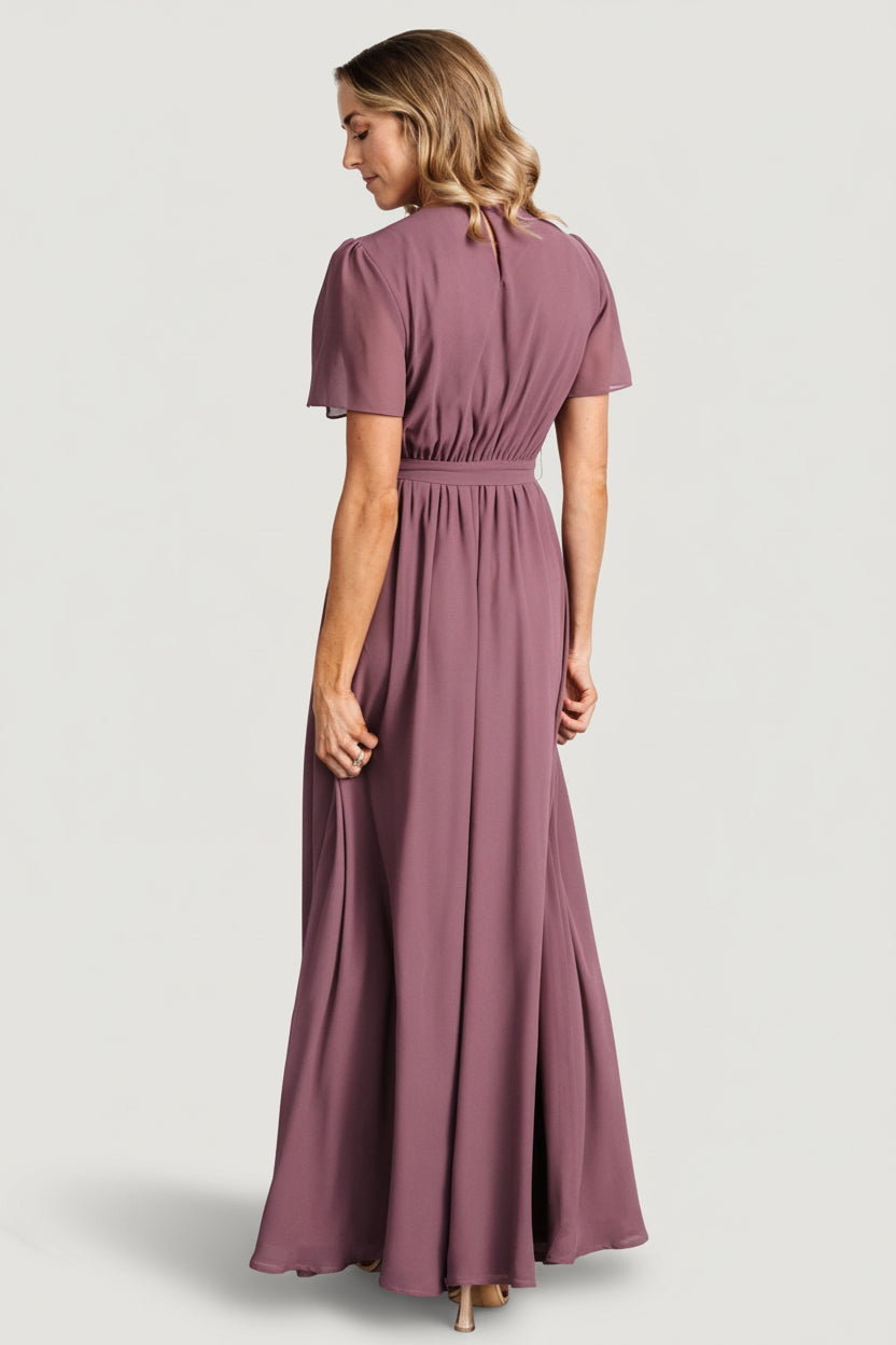 Model styling of Naomi dress with removable belt tied at natural waist and short flutter sleeves for a feminine silhouette in vintage plum.