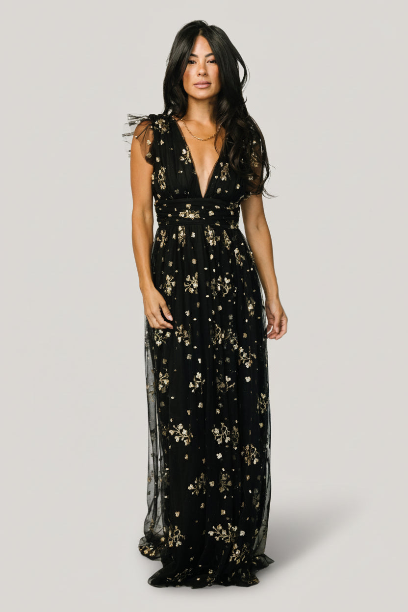 Three-quarter view of Natalia maxi highlighting tulle frill sleeve detail, sparkling floral pattern, and flowing maxi skirt with left-side leg slit.