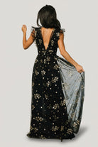 Close-up of floral embellishments and sequin detail on black fabric showing texture, sparkle, and the layered tulle accents at the sleeve edge.
