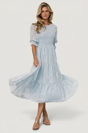 Front view of Nellie Smocked Midi Dress in light blue chiffon with burnout botanical print, showing smocked bodice and puffed poet sleeves.