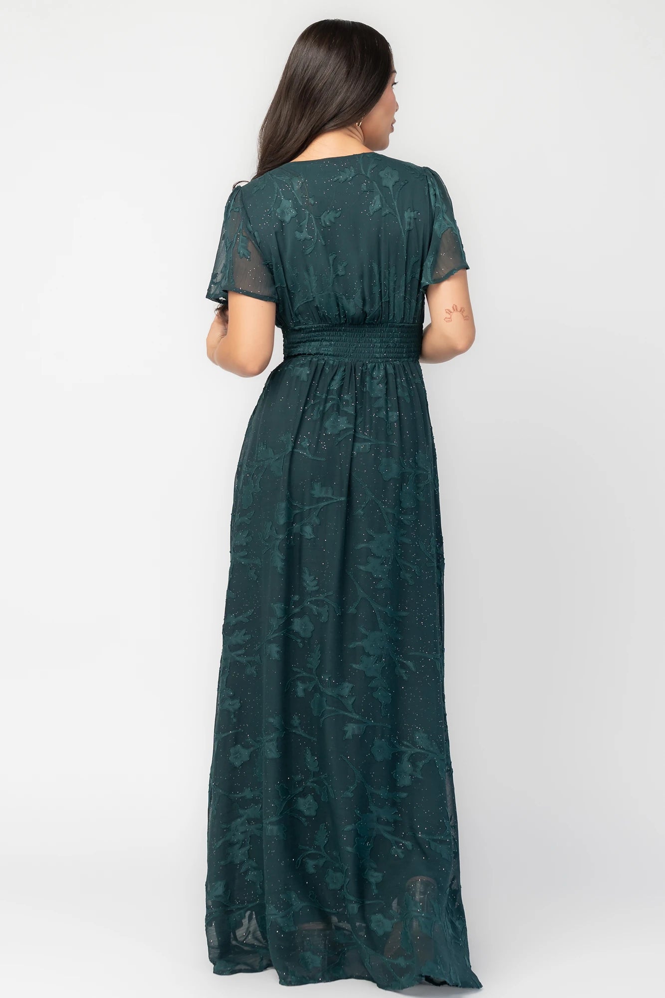 Noelle Maxi Dress in Dark Green Floral with silver sparkle, deep V-neck, flutter sleeves, smocked waist, and flowy skirt.