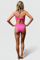 Back view showing moderate coverage and ribbed texture of the pink Oakland bikini bottom with a supportive, mid-rise banded waist.
