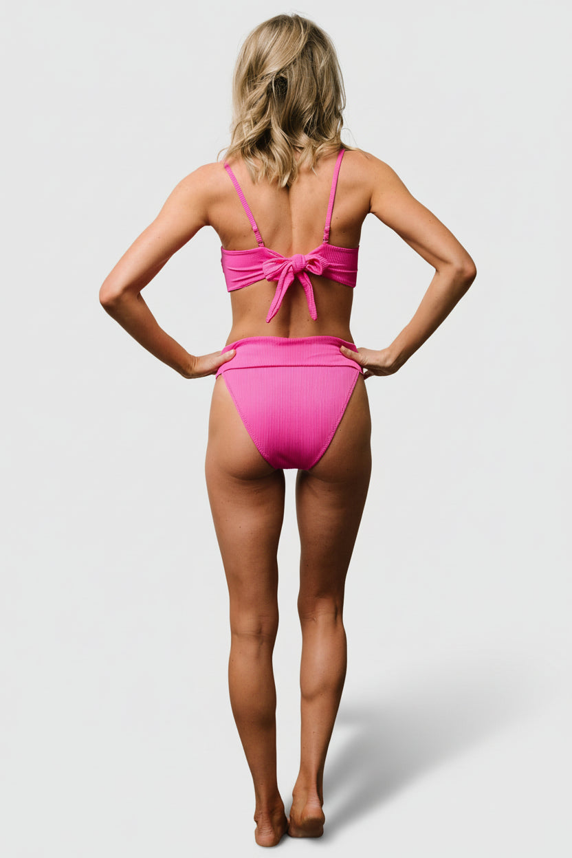 Back view showing moderate coverage and ribbed texture of the pink Oakland bikini bottom with a supportive, mid-rise banded waist.