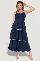 Front view of navy-and-white Odette tiered midi dress showing V-neckline, embroidered triangle accents, and overlapping tiers for movement.