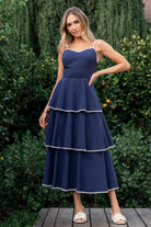 Styled flat-lay or on-figure shot of navy-and-white Odette dress, showing overall shape, V-neck, and embroidered contrast details.