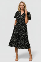 Model wearing Odeya tiered midi dress in black-and-white floral, styled with relaxed sleeves and empire waist.