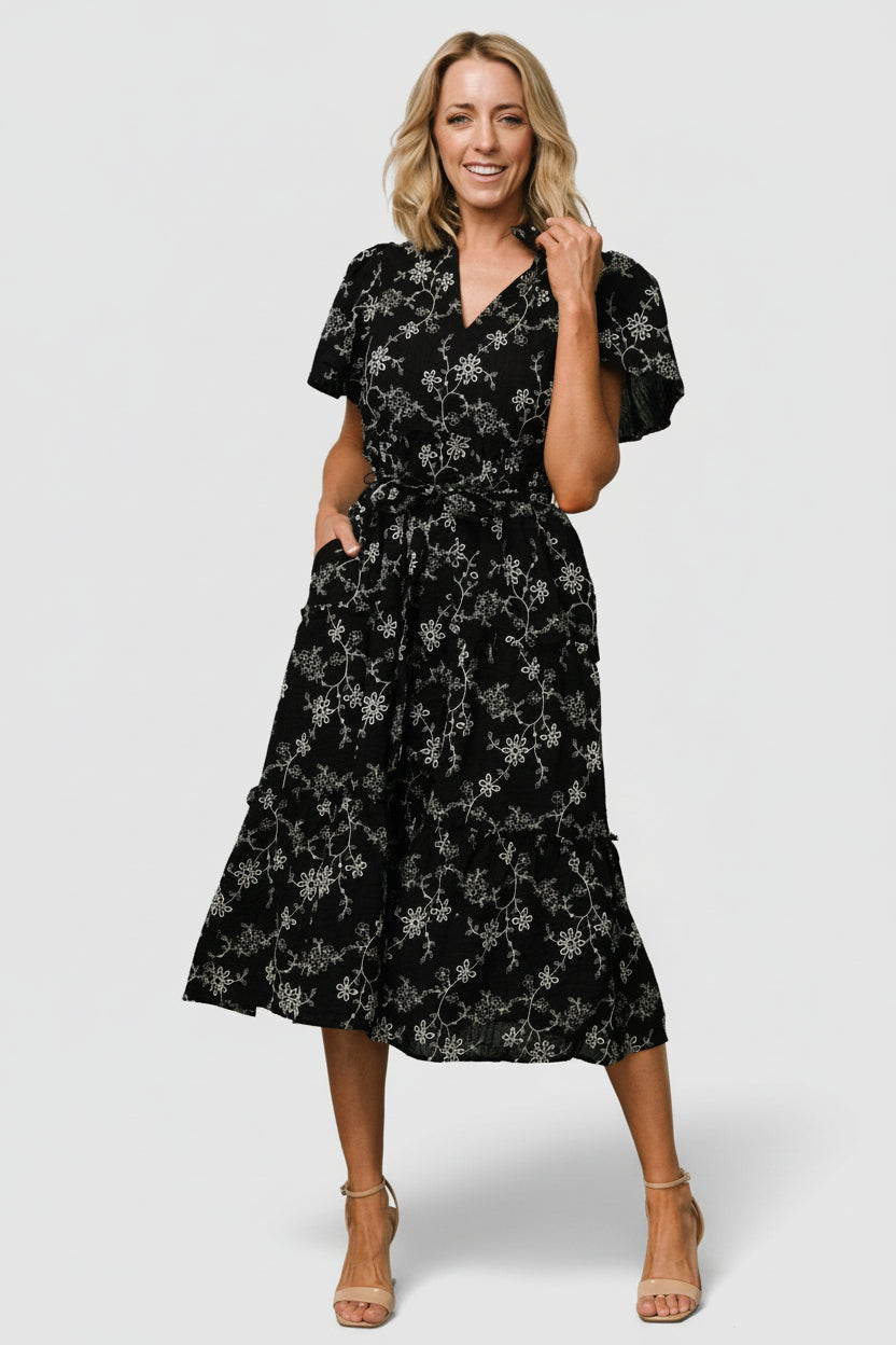 Model wearing Odeya tiered midi dress in black-and-white floral, styled with relaxed sleeves and empire waist.