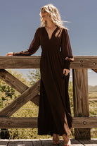 Front view of Olivia chiffon maxi dress in deep espresso brown on model, showing deep V-neck, smocked waist, long sheer sleeves.