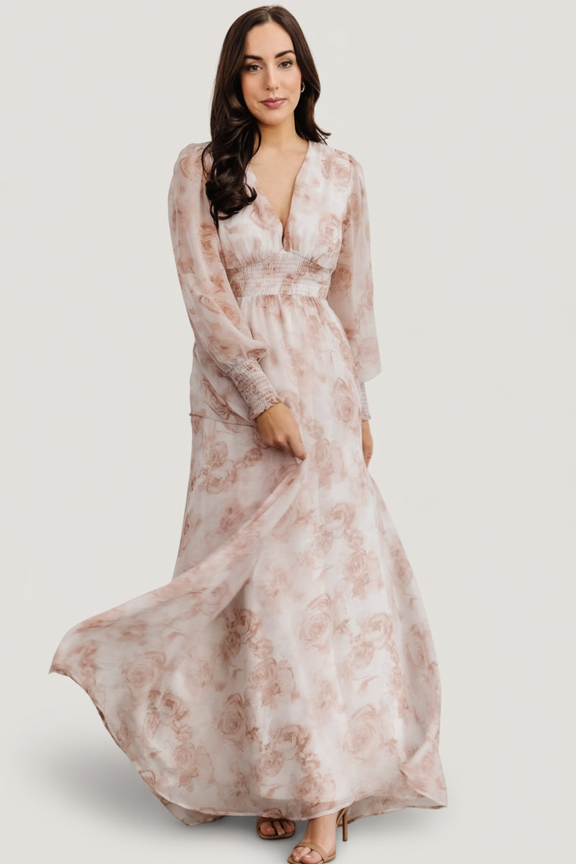 Front view of pink floral chiffon maxi dress with deep V-neck, smocked waist, long smocked sleeves, and flowing skirt for feminine movement.