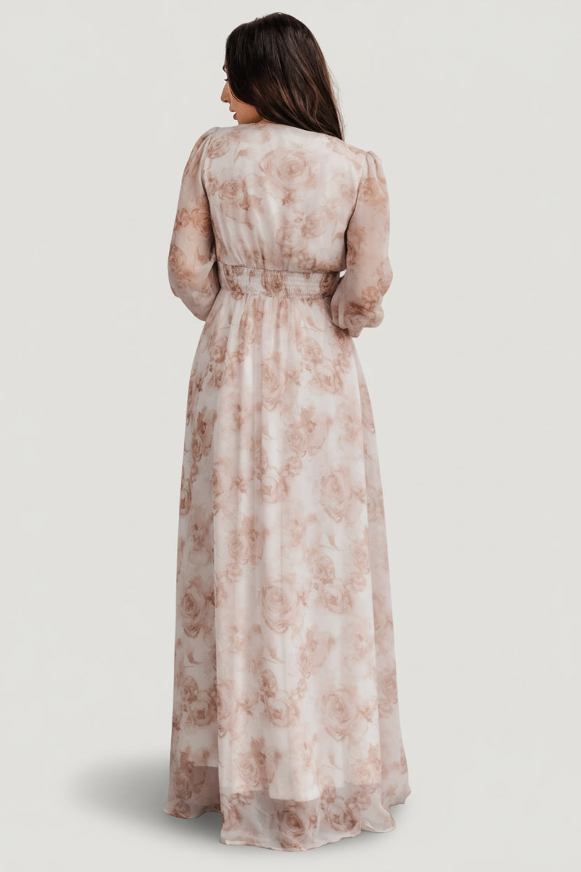 Side profile of pink floral chiffon maxi dress showing silhouette, full-length skirt, and smocked cuff detail at the sleeve.