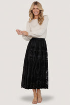 Three-quarter side view of the black Palini Velvet Midi Skirt highlighting the drape and movement of the velvet-burnout mesh over lining.