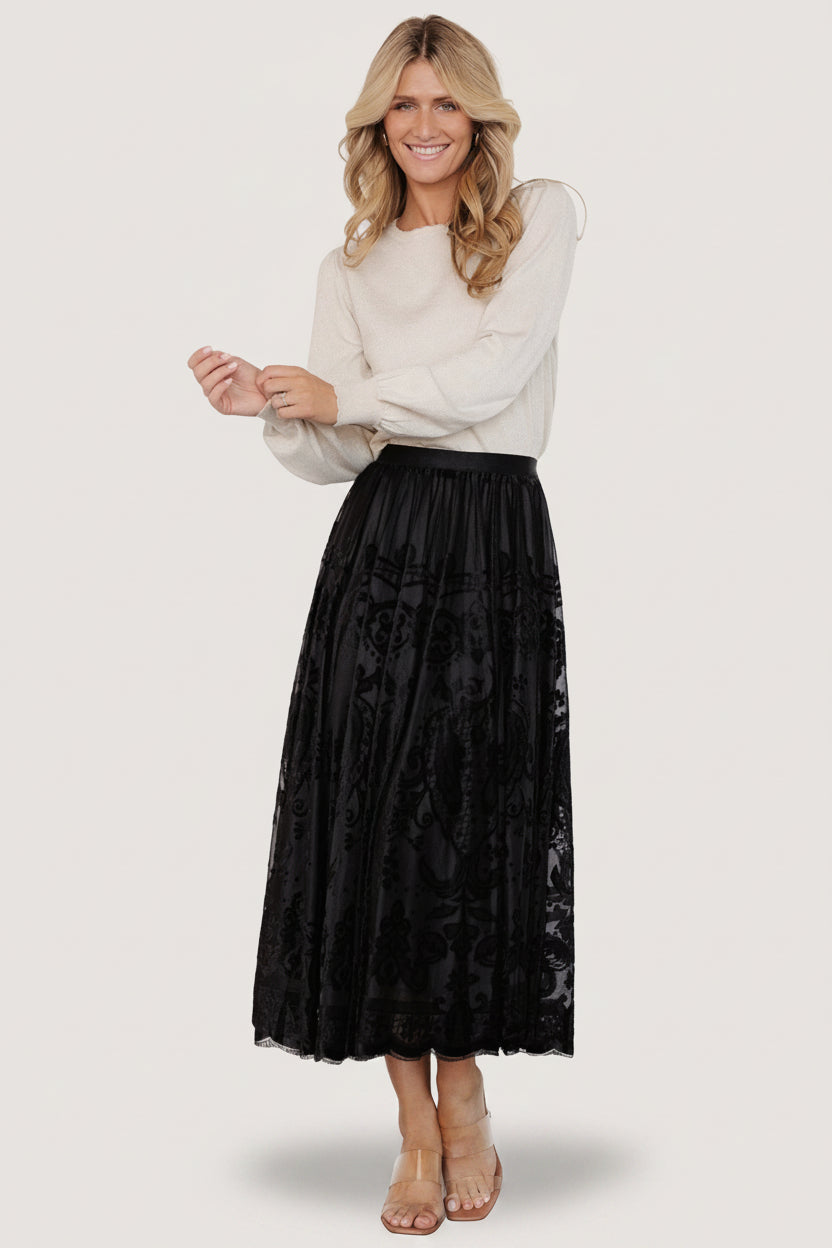 Three-quarter side view of the black Palini Velvet Midi Skirt highlighting the drape and movement of the velvet-burnout mesh over lining.