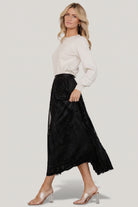 Back and side view of the Palini Velvet Skirt in black, showing the full lining, elastic waistband, and midi-length silhouette on model.