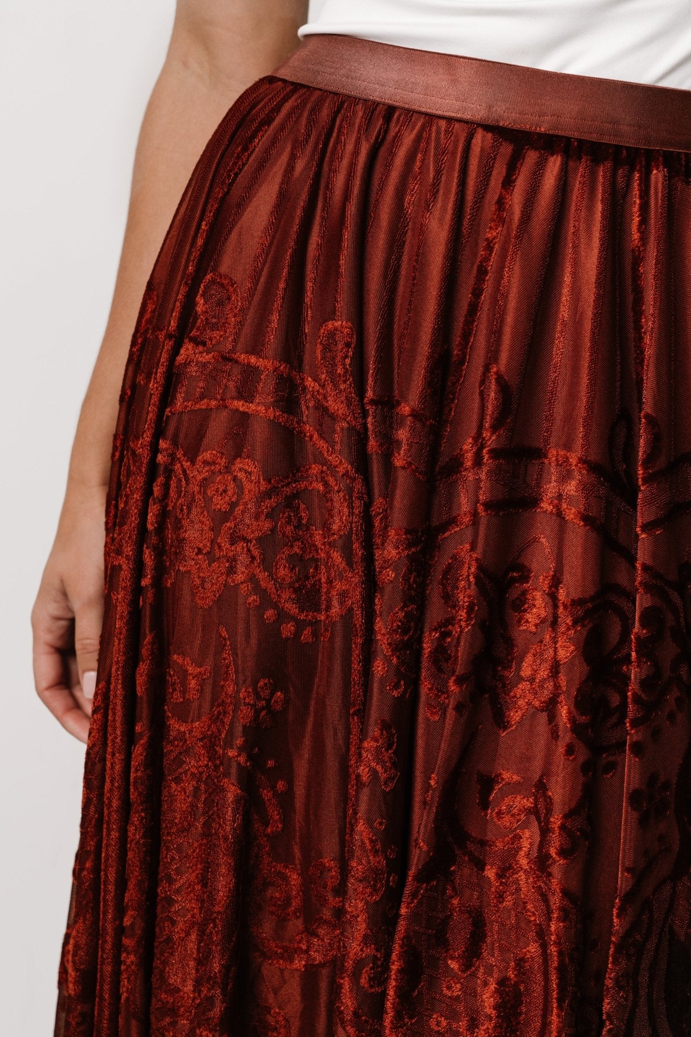 Close-up of Palini skirt fabric showing velvet burnout pattern over rust lining and soft mesh texture.