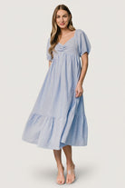 Model wearing Poppy Midi Dress in blue and off-white stripes, demonstrating fit at the empire waist, smocked back, and side pockets.