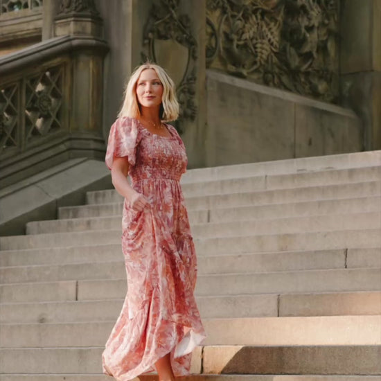 Model wearing the Southampton Smocked Maxi Dress in Dusty Mauve Floral featuring a square neckline, flutter sleeves with ruffle trim, a fully smocked bodice, and a flowing tiered maxi skirt with a dusty mauve floral print.