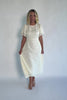 Model wearing a cream midi dress with a round neckline, short gathered sleeves, and a fitted bodice.