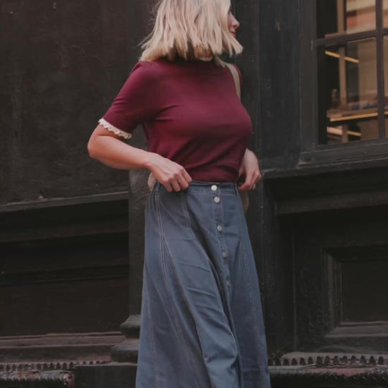 Model wearing the Adeline Sweater Top in Wine featuring a mock neckline, short sleeves with gathered shoulders, contrast ivory eyelet ruffle trim at the neckline and cuffs, and a classic fitted knit silhouette.