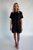 Model wearing a black short shift dress embellished with green sequins and floral appliqué detailing.