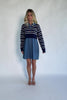 Model wearing a navy and ivory striped sweater dress with a collared neckline, functional button-front detail, long sleeves, and an elastic waist.