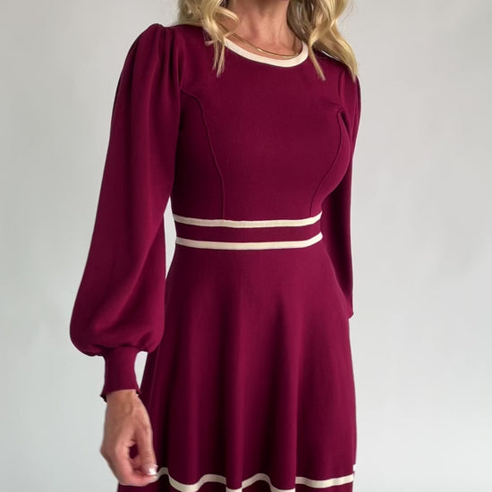 Rich wine knit mini dress with cream contrast trim, long balloon sleeves, a fitted waist, and a flared skirt.