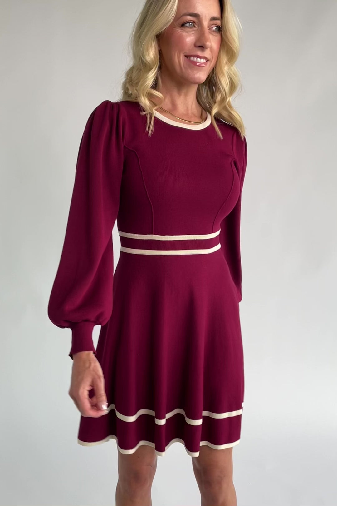 Rich wine knit mini dress with cream contrast trim, long balloon sleeves, a fitted waist, and a flared skirt.