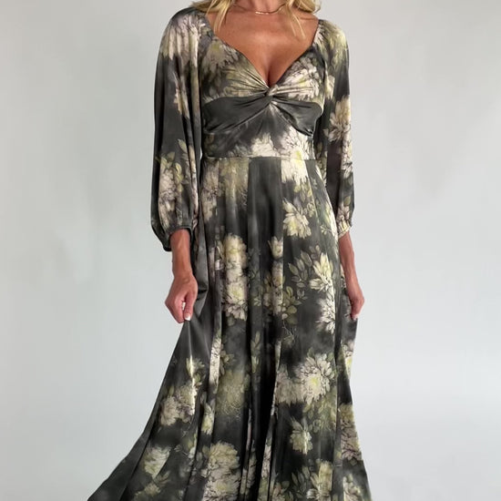 Dark sage floral maxi dress with a V-neck twist knot, half sleeves, smocked back waist, paneled empire waist, and flowing scalloped asymmetrical hem.