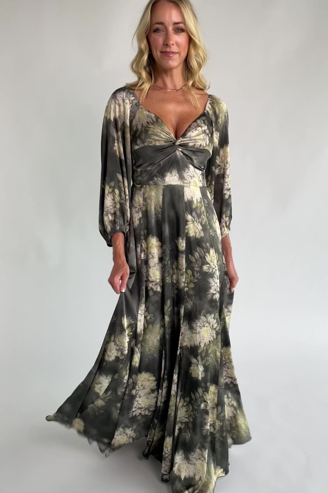 Dark sage floral maxi dress with a V-neck twist knot, half sleeves, smocked back waist, paneled empire waist, and flowing scalloped asymmetrical hem.