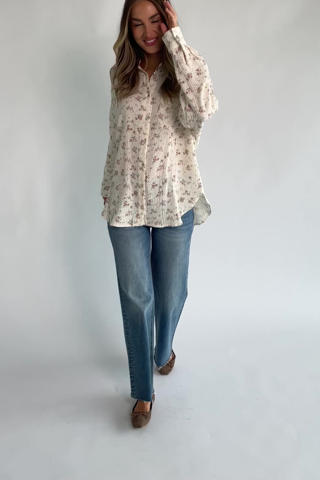 Ivory floral button-front blouse with a collared neckline, long sleeves, front patch pocket, relaxed oversized fit, and rounded high-low hem.