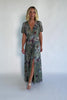 Model wearing a sage floral maxi dress with a deep V-neckline, short flutter sleeves, and an empire waist.