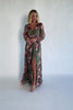 Model wearing a green floral maxi dress with a V-neckline, long bishop sleeves, and a gathered waist with a smocked back.
