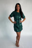Model wearing a green short shift dress embellished with green sequins and floral appliqué detailing.