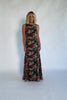 Model wearing a topaz floral maxi dress with a high round neckline, sleeveless bodice, and an open back with a sash tie.