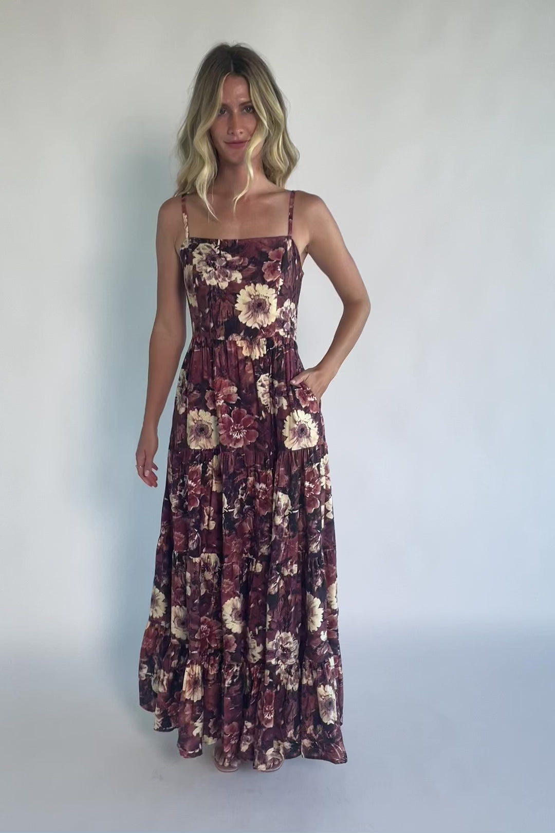 Model wearing a deep berry floral maxi dress with a square neckline, adjustable spaghetti straps, and a smocked back bodice.