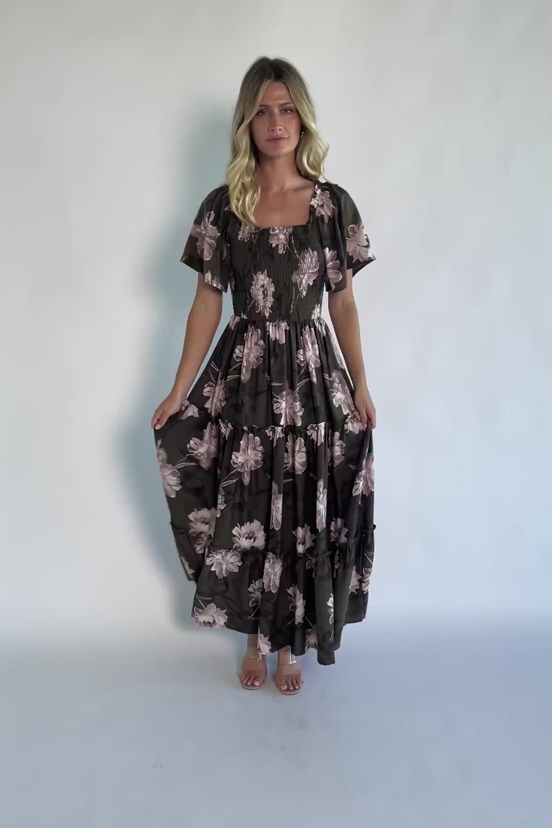 Dark olive floral maxi dress with a smocked bodice, square neckline, flutter sleeves, and a tiered ruffle skirt.
