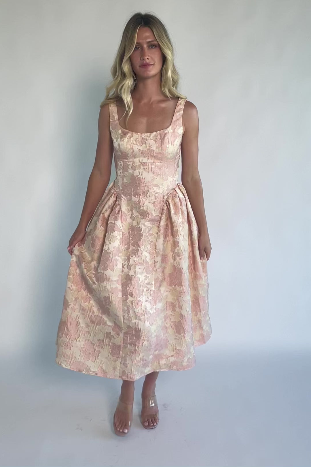 Model wearing a peach floral jacquard midi dress with a square neckline, wide tank straps, and a fitted bodice.